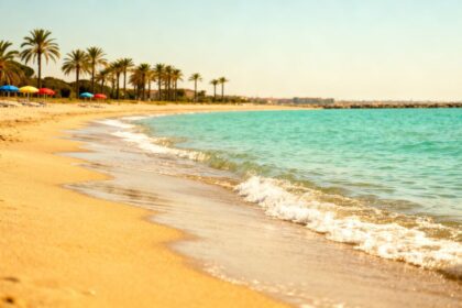 Ruhiger Strand auf Lido di Venezia mit goldenem Sand und türkisfarbenem Wasser.