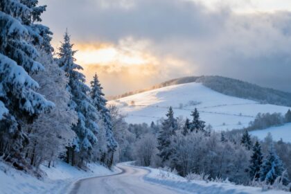 Ruhige verschneite Landschaft im Sauerland mit Bäumen und Hügeln.