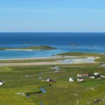 Coastal village nestled in green fields by the ocean.