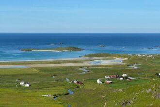 Coastal village nestled in green fields by the ocean.