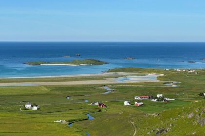 Coastal village nestled in green fields by the ocean.