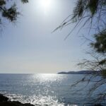 the sun is shining over the water and rocks