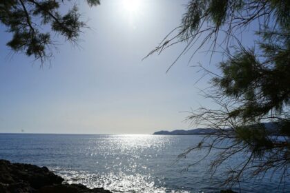 the sun is shining over the water and rocks
