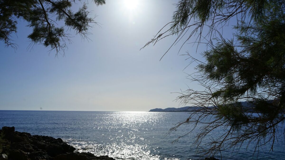 the sun is shining over the water and rocks