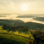the sun is shining over a green valley