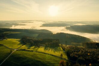 the sun is shining over a green valley