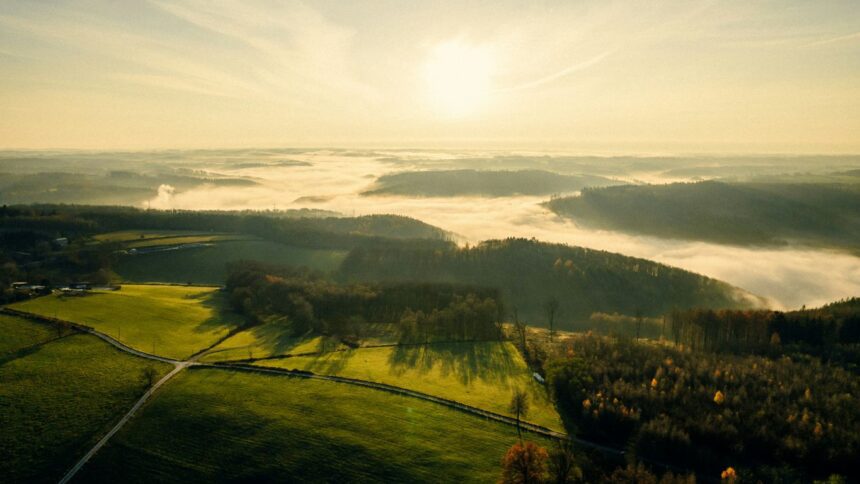 the sun is shining over a green valley