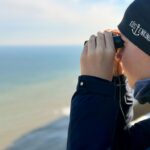 Person looking through binoculars at the ocean