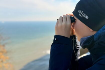 Person looking through binoculars at the ocean