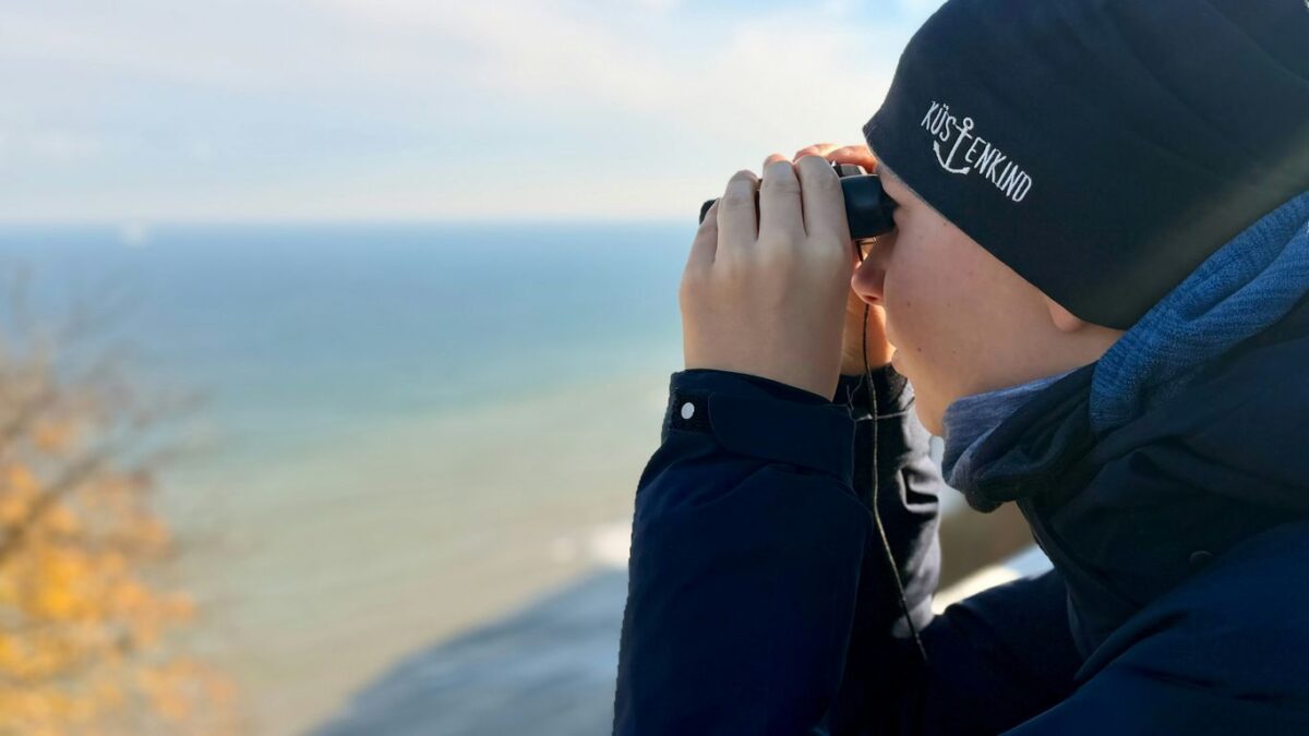 Person looking through binoculars at the ocean