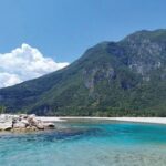 A turquoise river flows before a mountain.